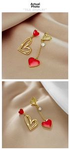 Detail of red enamel heart and gold hollow heart earrings with dangling chain tassels