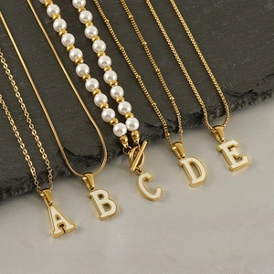 Gold stainless steel initial necklaces with white letter pendants and varied chain styles