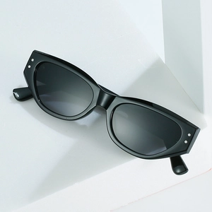 Retro cat-eye sunglasses in glossy black with silver rivets on a white geometric block