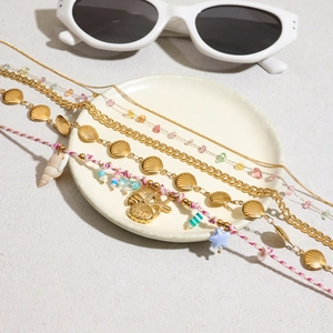 Boho-Fußkettchen-Set in Gold mit Seestern- und Muschel-Anhängern auf Sandboden