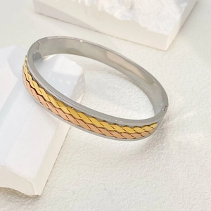 Detailed close-up of tricolor interwoven metal cuff bracelet in gold, silver, and rose gold