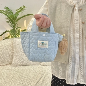 Detailed shot of a light blue heart-quilted handbag with a cute brown plush charm