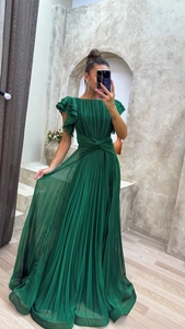 Detail view of deep green pleated evening dress featuring ruffle sleeves and waist twist design