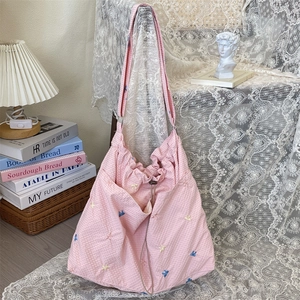 Borsa tote in tela a quadretti rosa con fiocchi ricamati su un tavolo decorato