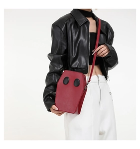 Close-up of a red coffin-shaped crossbody bag made of PU leather with gothic design