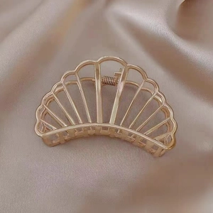 Detailed view of a 7.5cm gold-toned fan-shaped metal hair claw clip with cutout design