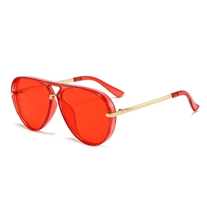 Detail of red lenses and gold metal frame of large aviator sunglasses from 45-degree angle