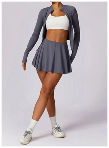 Detail van geplooide tennisrok met hoge taille met vest met rits en sportbeha