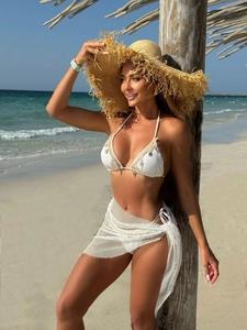 Detail of white textured bikini with shell pendants and sheer mesh wrap skirt