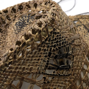 Macro detail of hand-woven natural straw with dark painted textures on a western hat