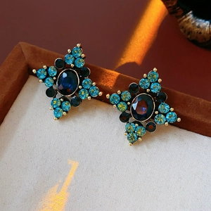 Dettaglio di orecchini vintage con pietra ovale blu scuro e piccoli cristalli azzurri