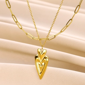 Detailed shot of double-layered gold heart pendant necklace with trendy paperclip link chain