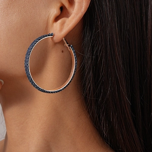 Close-up of model wearing dark blue denim fabric hoop earring with glitter texture