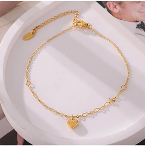 Detail of gold heart pendant anklet with adjustable chain on a white tray