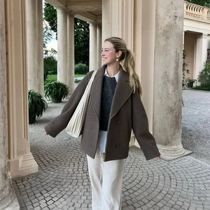 Brown double-breasted wool short coat styled with trousers in a scenic outdoor setting