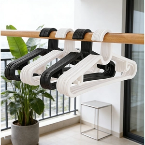 Durable black and white plastic clothes hangers with non-slip notches in a balcony setting