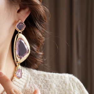 Detail of vintage gold earrings with purple gemstones shown on a model