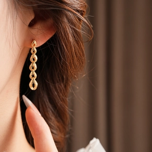 Vue détaillée de longues boucles d'oreilles dorées à pampilles texturées sur un modèle