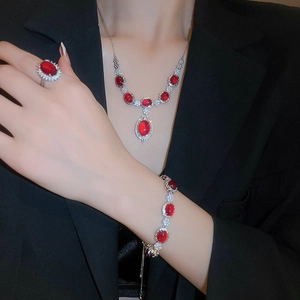 Close-up of red gemstone jewelry set with necklace and ring on a black suit model