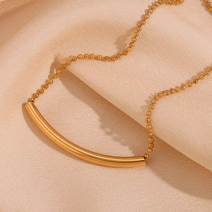 Detailaufnahme der 18K vergoldeten Smile-Halskette auf weichem rosa Seidenstoff