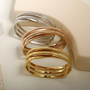 Detailed view of layered 18K gold plated steel wire bracelets in silver, gold and rose gold