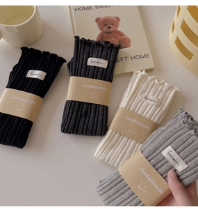 Set of four ribbed knit socks in neutral tones with frilly edges and cozy home decor
