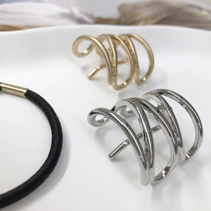 Minimalist gold and silver hollow metal hair clips with black elastic hair tie on white plate