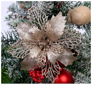 Gros plan d'un poinsettia évidé or champagne avec paillettes sur un sapin de Noël