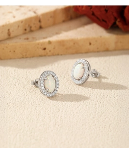 Detailed macro of S925 silver opal stud earrings with diamond halo on stone background