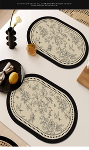 Detail of oval waterproof faux leather placemat with floral bird pattern and black piping