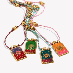 Detail of four handmade 18K gold tarot necklaces with colorful braided cords and charms