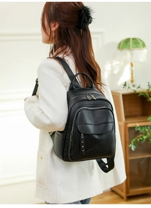 Close-up of black PU leather backpack showing lychee texture and silver rivet details