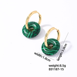 Gros plan sur des boucles d'oreilles en acier doré avec pendentifs en malachite verte