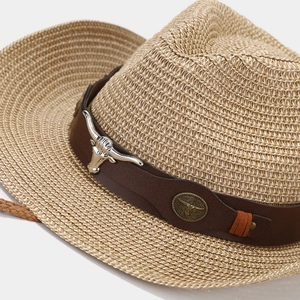Detailed macro view of western straw hat with leather band and bull head ornament