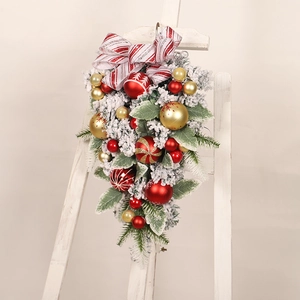 Detail of red stripe bow and festive gold baubles on snow-flocked Christmas teardrop swag