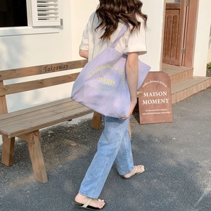 Chic lavender canvas tote bag with yellow typography shown in a casual street setting