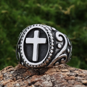Detailed view of vintage stainless steel cross ring placed on a textured tree bark