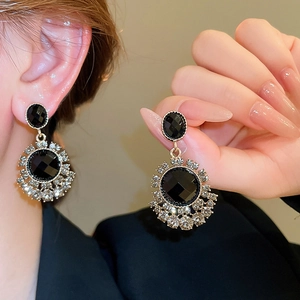 Macro shot of silver studs with black crystals and halo zircons shown on ear and hand