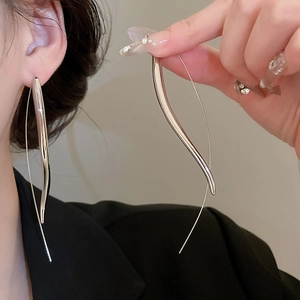 Detail showing sleek silver teardrop earrings with a streamlined minimalist curve design