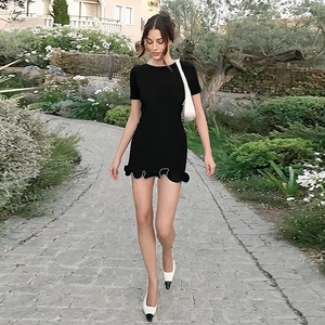 Détail d'une mini robe noire moulante avec ourlet à volants et col rond sur mannequin