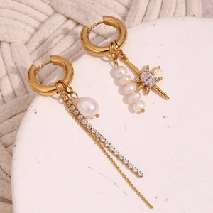 Detail of asymmetric gold star earrings featuring freshwater pearls and zircon chains