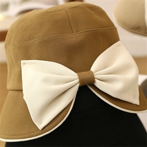 Detail of khaki cloche hat with a large cream bow and premium cotton fabric texture