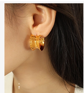 Detailed view of gold plated titanium earrings with unique wrinkled texture on a model