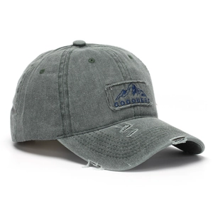 Detail of army green washed baseball cap featuring vintage embroidery and distressed holes