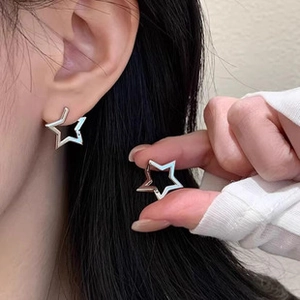 Close-up of minimalist silver hollow star earrings worn by a model to show product scale