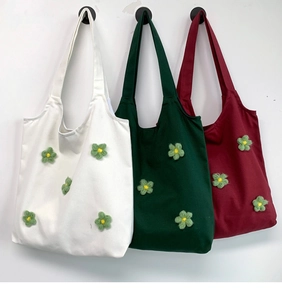 Detailed shot of three floral canvas tote bags hanging on a clean white wall background
