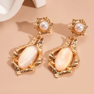 Macro shot of vintage gold shell earrings with pearl floral studs and oval pendants