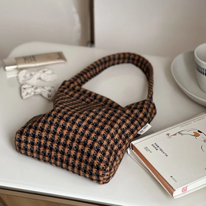 Close-up of a cozy plaid wool handbag with a brand tag on a warm lifestyle background