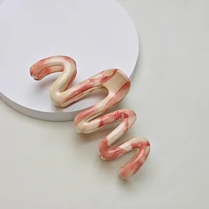 Detail of pink and white marble texture on a wavy S-shaped resin hair claw clip