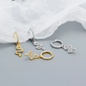 Close-up of gold and silver snake hoop earrings with white zircon stones for women